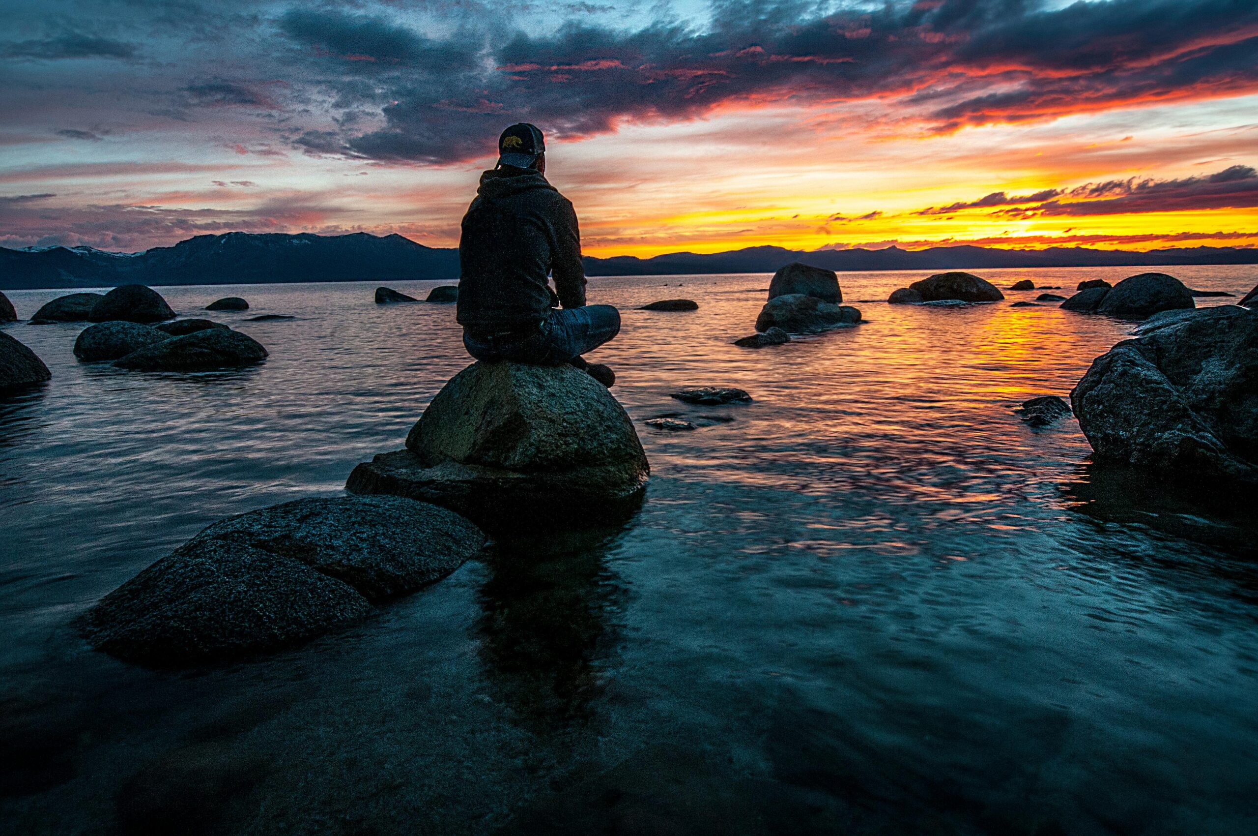 man sitting on rock in the water