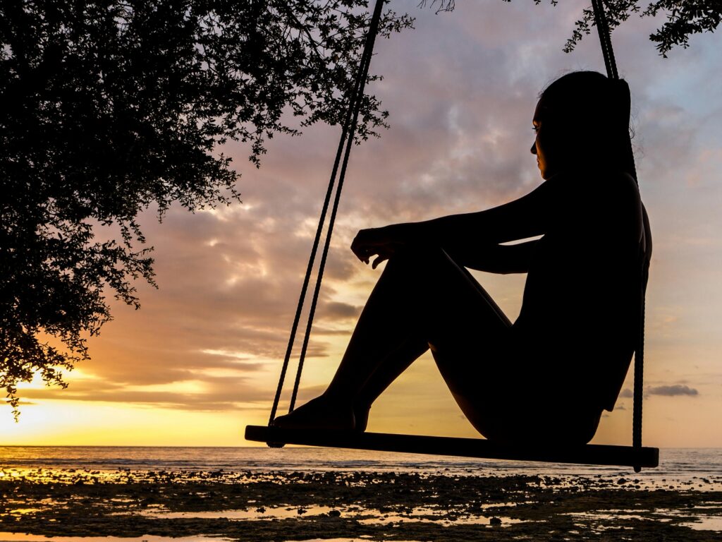 person on swing overlooking beach