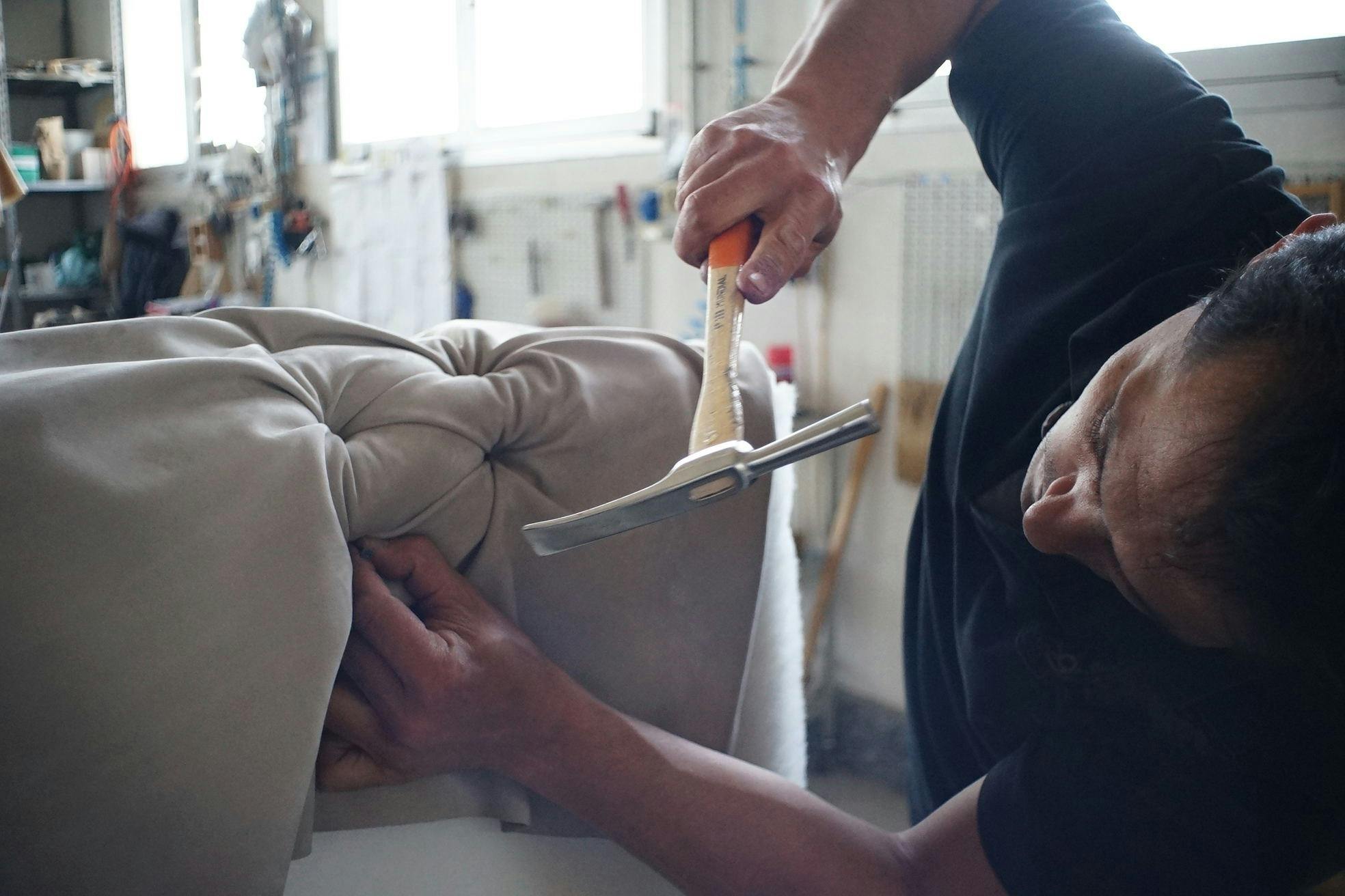 person hammering a nail into couch