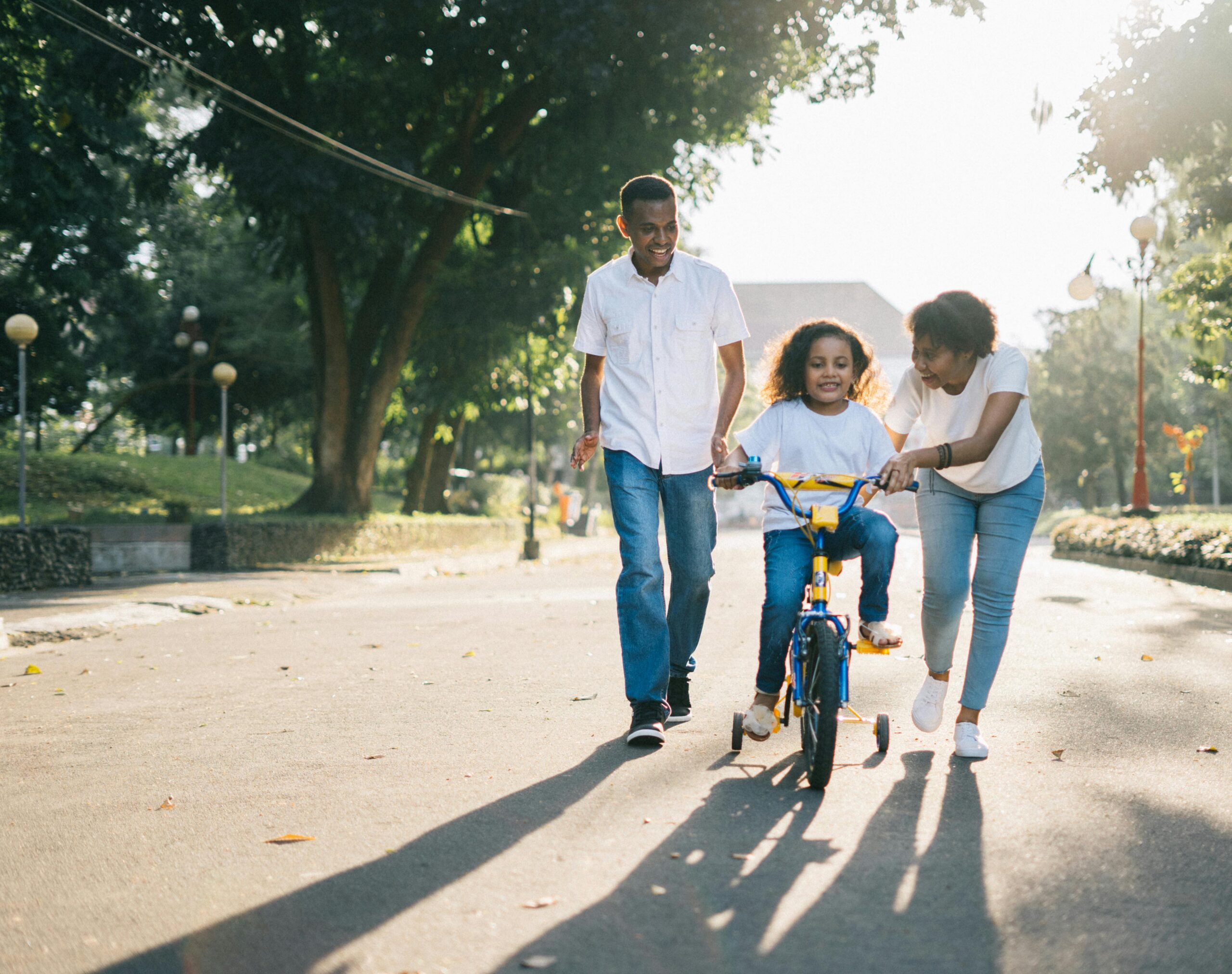 parents helping kid ride a bike